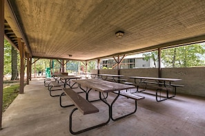 An outdoor covered picnic area with multiple picnic tables and benches.