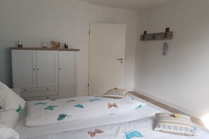 A bedroom with a bed, a wardrobe, a door, and a coat rack. - Herring in the Fisherman's House (Hohwacht)