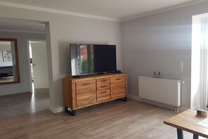 Quarto com armário de madeira, televisão de tela plana, radiador e mesa de madeira.