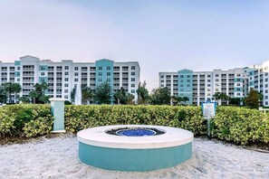 A hotel with multiple-story buildings, a circular water feature, and a sign indicating a fire circle. - Orlando | Orlando Resort Stay | Pool & Water Park | 2BR (Orlando)