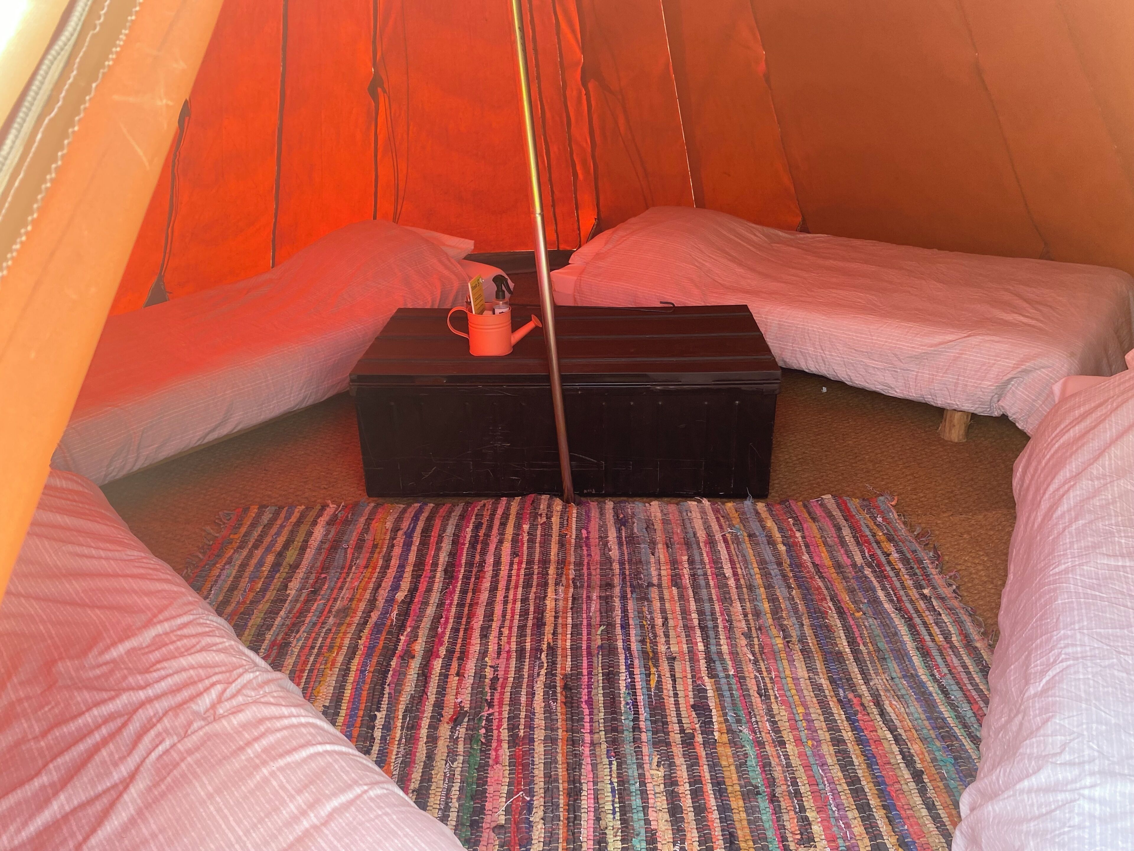 Una tenda amb dos llits, una taula petita i una alfàbbra colorida.