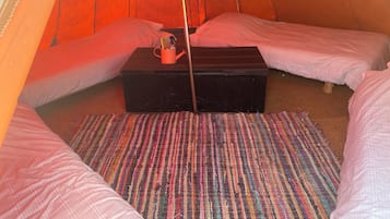 Una tenda amb dos llits, una taula petita i una alfàbbra colorida.