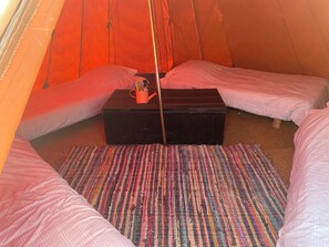 Una tenda con due letti, un tavolino e un tappeto colorato.