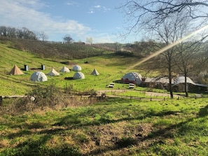 Paisaje rural con varias estructuras de domos geodésicos, un granero rojo y un área cercada con senderos.