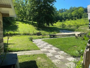 Un camino empedrado que lleva a un área de picnic con una terraza de madera y un pequeño estanque.