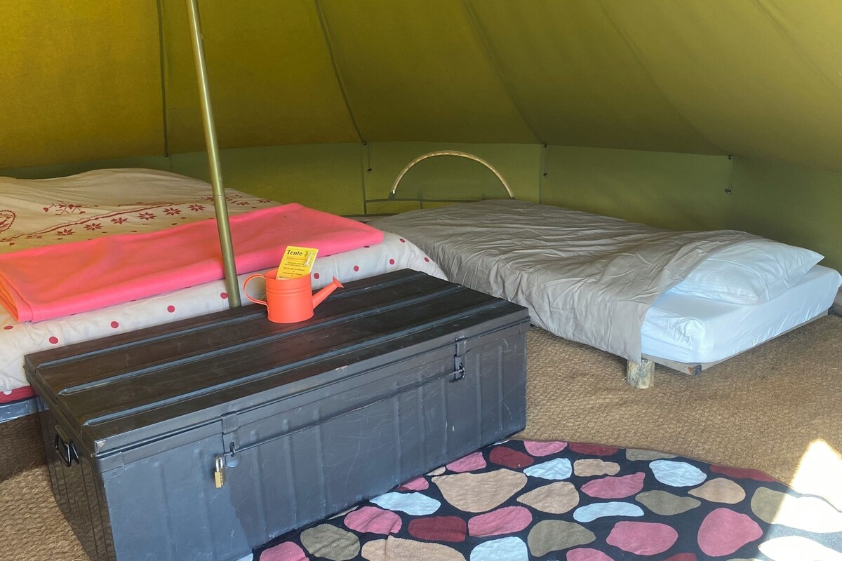 Una tenda con due letti, una valigia e un tavolino con un biglietto.