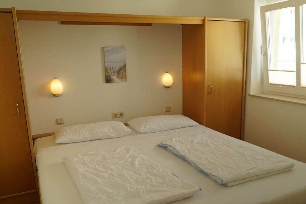 Ein Doppelbett mit zwei Kissen, einer Wandleuchte und einem Fenster.
