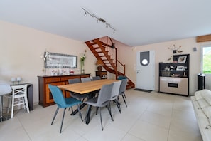 Eine moderne Küche mit einem Holzespeisetisch, grauen Stühlen, einem eingebauten Herd und einer Holztreppe.