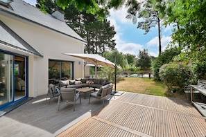 Eine moderne Außenpatio mit einer eingebauten Sitzecke, einem Esstisch und einem Grillbereich.