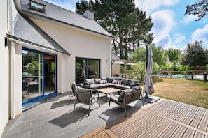 A modern house with a patio area featuring a sectional sofa, outdoor furniture, and a pool. - Ker Augusta - Jolie maison 4 chambres avec piscine (Mesquer)