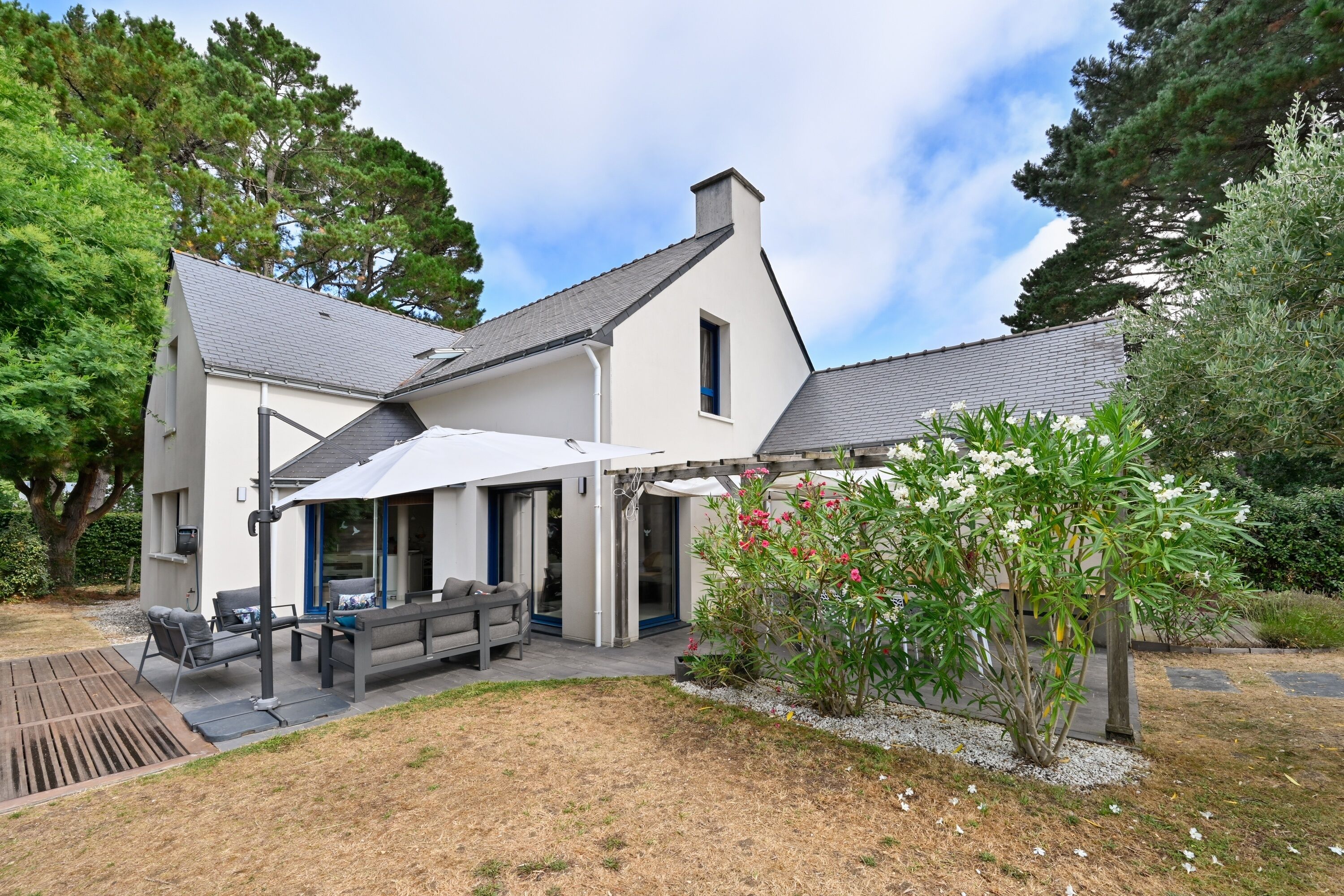 A modern house with a patio area, outdoor seating, and a garden.