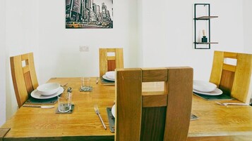 A dining table set with plates, cutlery, and glasses, surrounded by wooden chairs.