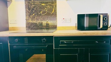 Una cocina con microondas, salpicadero de mármol y armarios de madera.