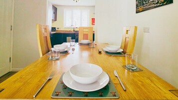 A dining table set with plates, bowls, glasses, and cutlery, with chairs around it.