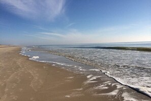 Una playa con cielo despejado y olas lamiendo suavemente la orilla.