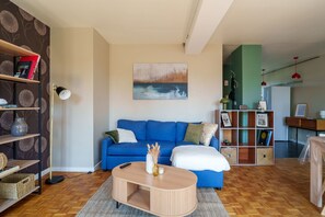 Ein Wohnzimmer mit einem blauen Sofa, einem Couchtisch und einem Bücherregal.
