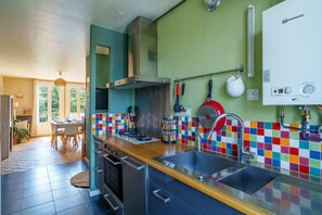 A modern kitchen with a gas stove, stainless steel sink, and colorful backsplash. - L’Écrin de Limoges - Grand studio avec parking (Limoges)