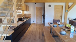 A compact kitchen with wooden cabinets, a built-in stove, and a wooden staircase. - Chalet Adenore - Triplex proche des pistes (Samoëns)