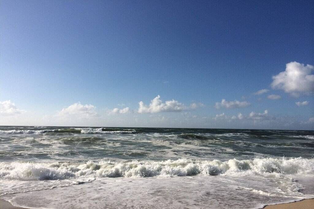 A beach with waves crashing onto the shore under a clear sky.