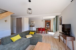 A modern living room with a sectional sofa, a dining table, and a TV. - Ty Liv - Maison familiale avec un beau jardin (Saint-Gildas-de-Rhuys)
