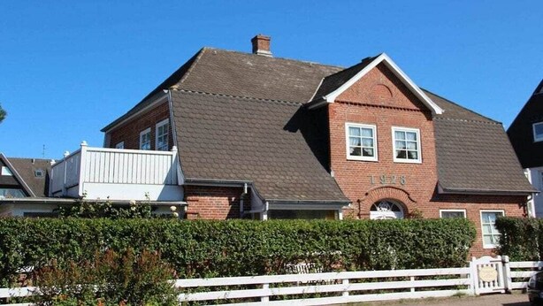 A two-story brick house with a gabled roof and a white fence in front. - Bötticher Str. 6 Holiday Apartment 3 (Sylt \/ OT Westerland)