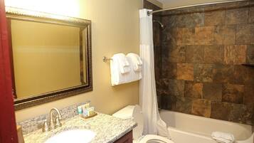 Une salle de bain avec un lavabo en marbre, des toilettes, une baignoire et un rideau de douche.