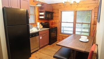 Une cuisine de taille réduite équipée d’un réfrigérateur, d’une cuisinière, d’un four à micro-ondes et de meubles de rangement en bois.