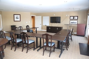 A conference room with a long table, chairs, a whiteboard, a TV, and framed pictures on the walls.