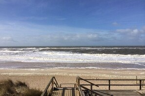 A wooden boardwalk leading to a beach with waves crashing onto the shore. - Fischerweg 15i Ground Floor (Sylt \/ OT Westerland)