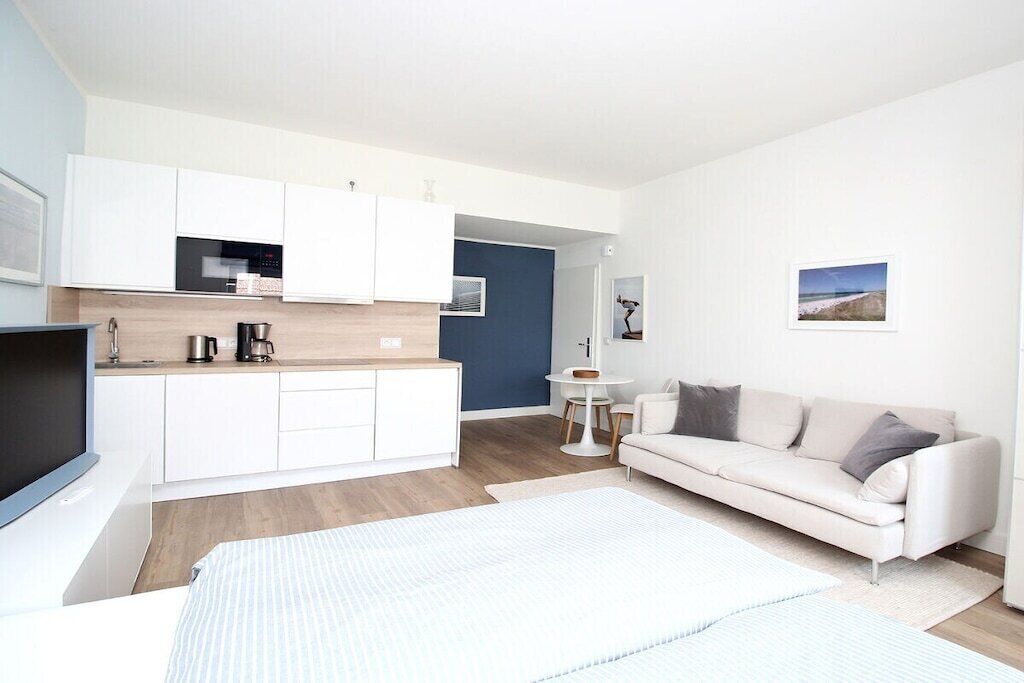 Un apartamento moderno con kitchenette, un sofá, una cama y una pequeña mesa de comedor.