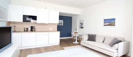 Un apartamento moderno con kitchenette, un sofá, una cama y una pequeña mesa de comedor.