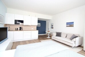 Un apartamento moderno con kitchenette, un sofá, una cama y una pequeña mesa de comedor.
