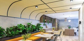 A modern interior with a curved ceiling, green plants, wooden seating, and a kitchen area. - Studio em Sao Paulo a 300m do Shopping Paulista (São Paulo)