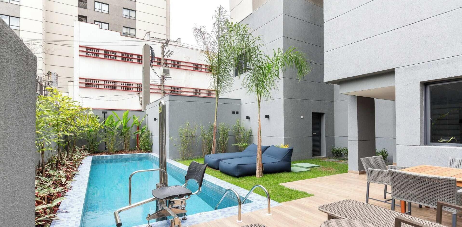 A modern outdoor pool area with a lounge chair, a small table, and a sofa.