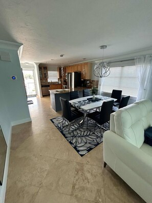 A spacious living area with a dining table, chairs, and a sofa. - 2bd Condo close to pool and restaurants  (Siesta Key)