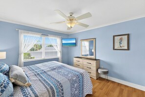 A bedroom with a bed, a dresser, a ceiling fan, a TV, and a window with curtains. - 2bd Condo close to pool and restaurants  (Siesta Key)