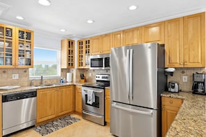 A modern kitchen with wooden cabinets, stainless steel appliances, and a window providing natural light. - 2bd Condo close to pool and restaurants  (Siesta Key)