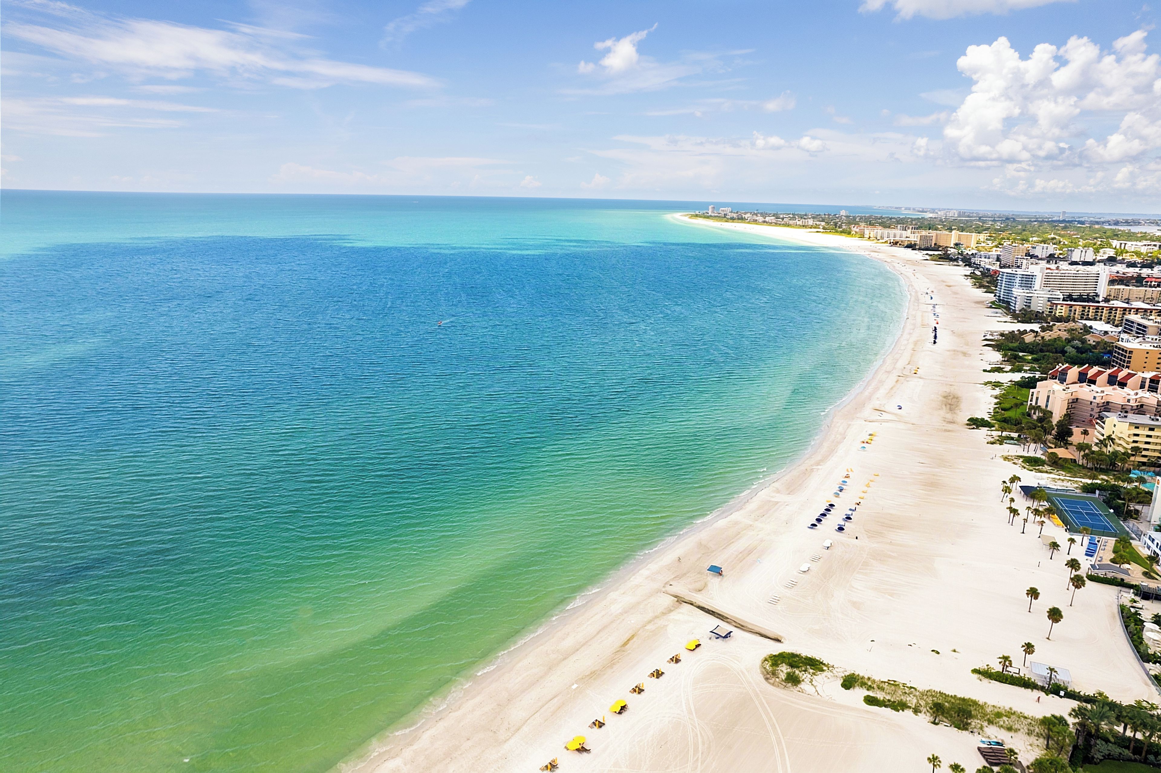Eine Küstenlandschaft mit Strand, Blick auf das Meer und angrenzenden Gebäuden.