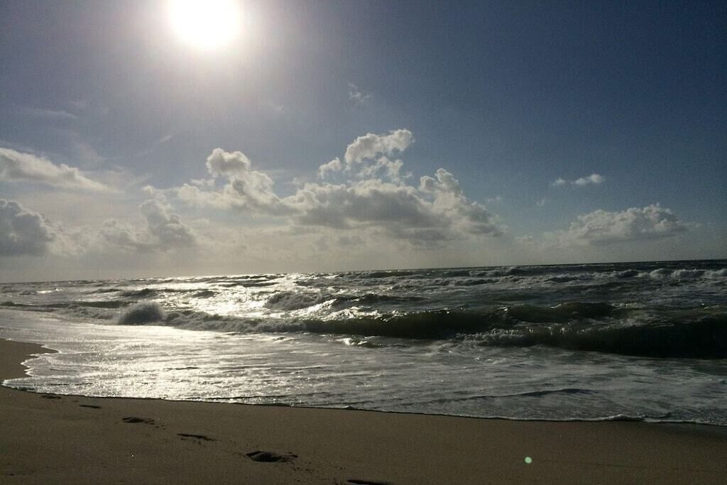 Une plage avec des vagues et des empreintes de pas dans le sable.