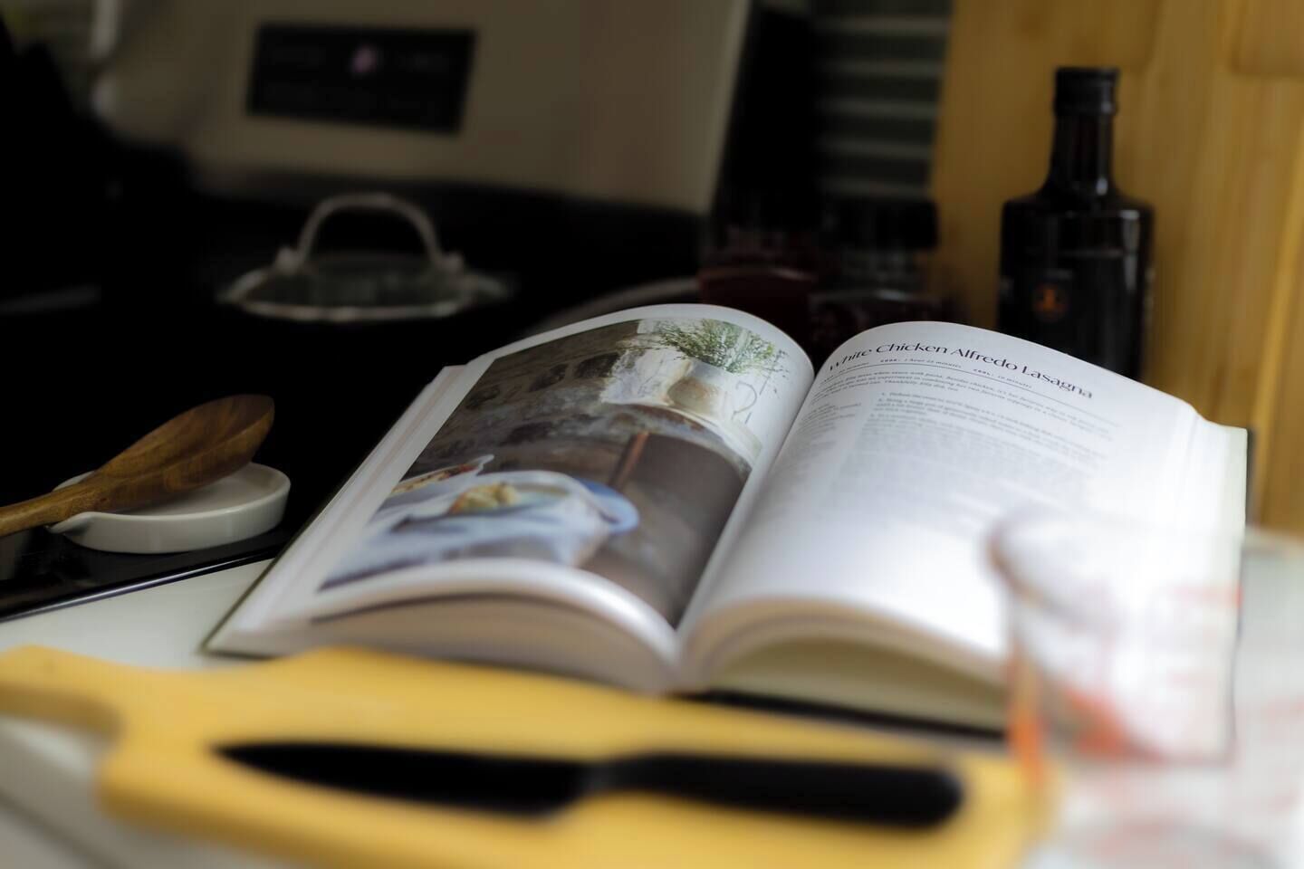 An open book with a photograph on the left page and text on the right page, placed on a table with a knife and a spoon nearby.