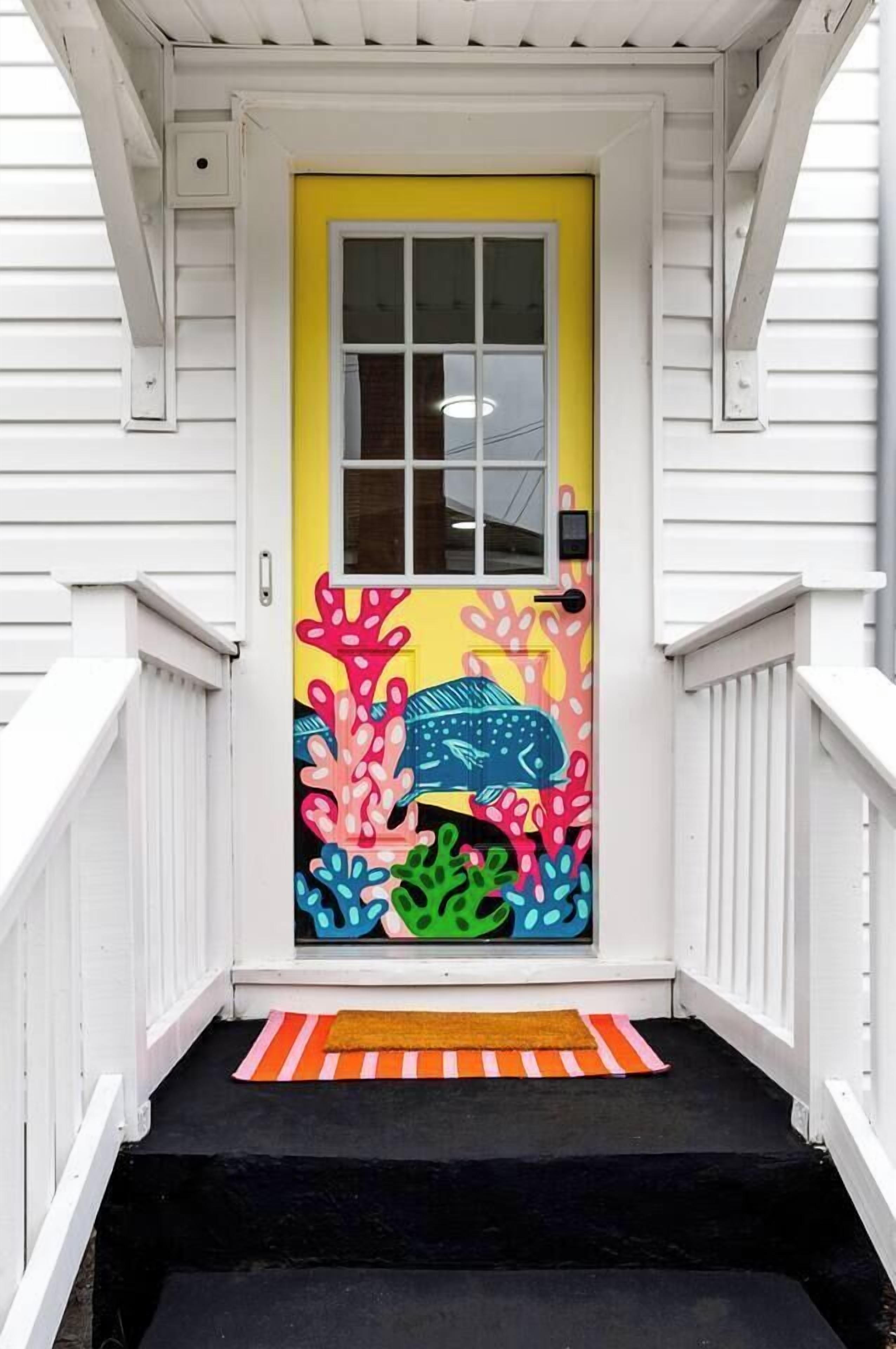 A house with a bright yellow door, a black front step, and a white railing.