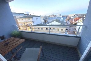 Un balcón con vistas a la ciudad, una mesa de madera y una silla.