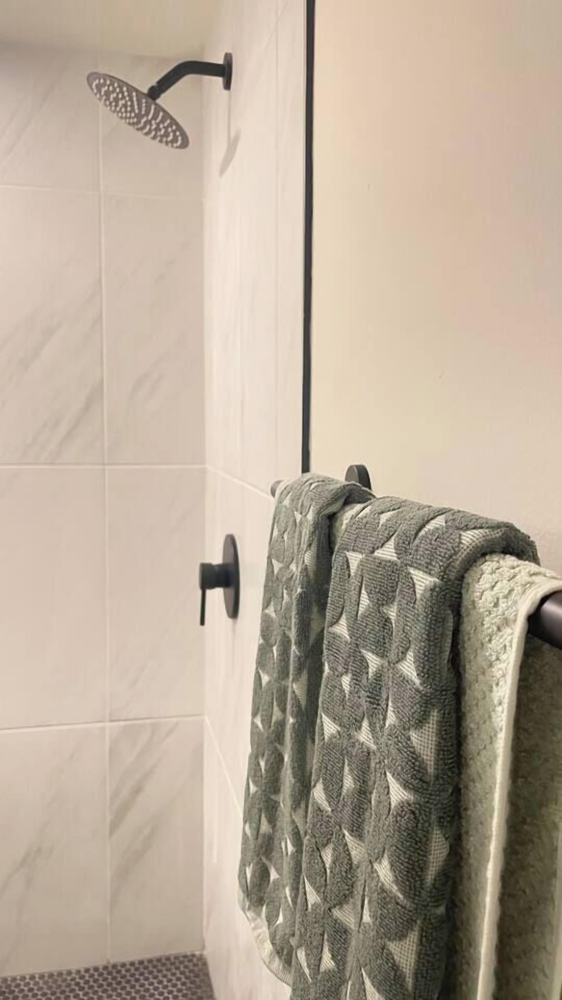 Ein Badezimmer mit Dusche, gefliesten Wänden und einem Handtuchhalter mit einem gemusterten Handtuch.
