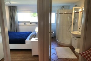 Un dormitorio con cama, mesita de noche y ventana con cortinas.