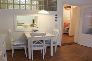 Un área de comedor con una mesa y sillas, un espejo sobre la mesa y vistas a un cuarto con mantel a cuadros rojo y blanco.