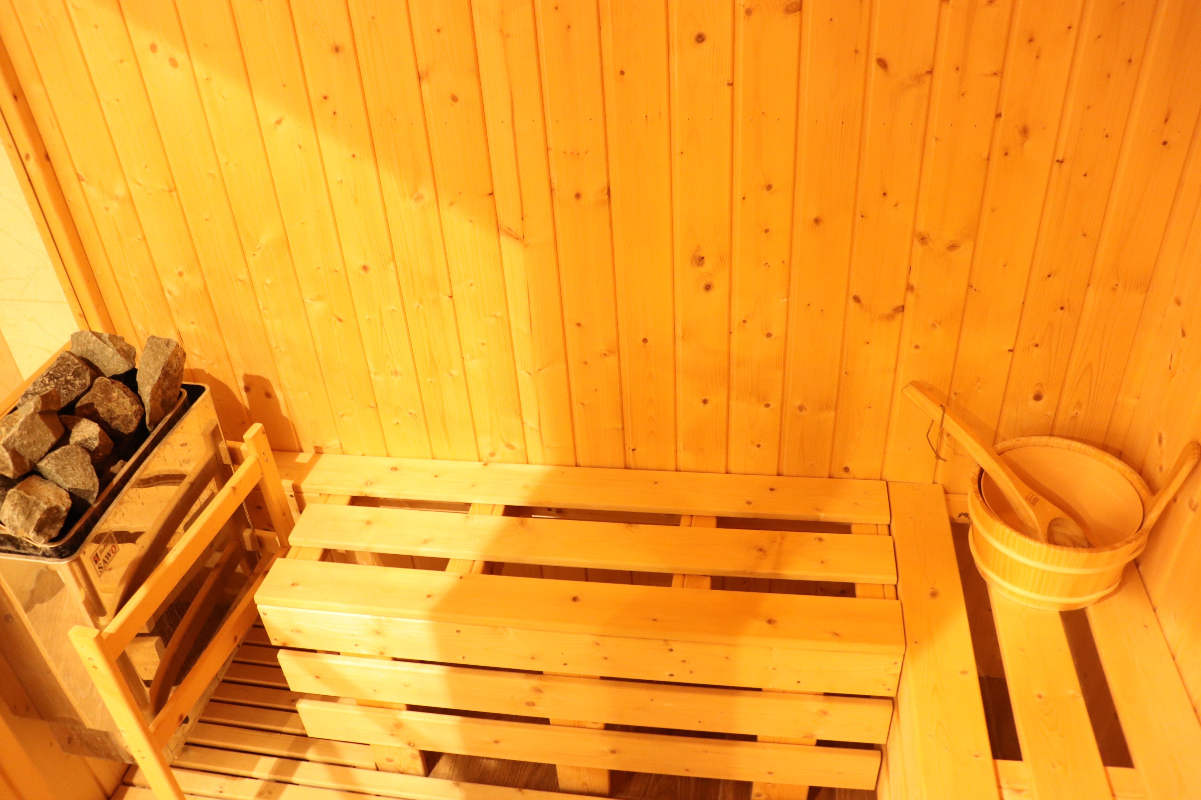 Una sauna con bancos de madera y un recipiente de piedra.