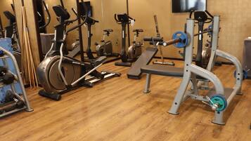 Un gimnasio con equipos de ejercicio variados, incluyendo cintas de correr, bicicletas estáticas y máquinas de pesas.