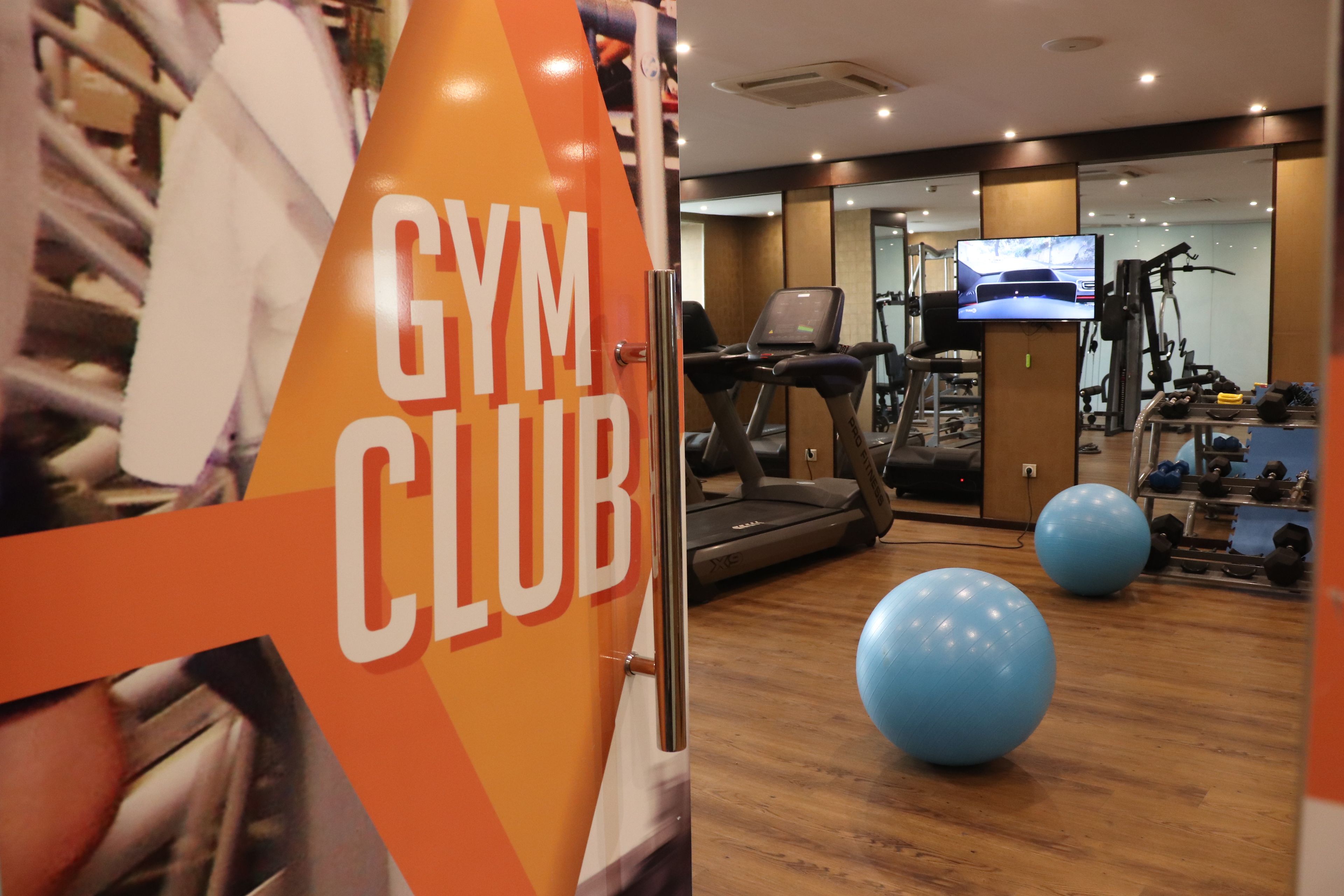 A gym with exercise equipment, a treadmill, and a television screen.