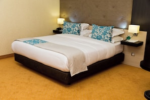 A hotel room with a large bed, two bedside tables, and a headboard. - NEWDAY (HUSSEIN DEY)