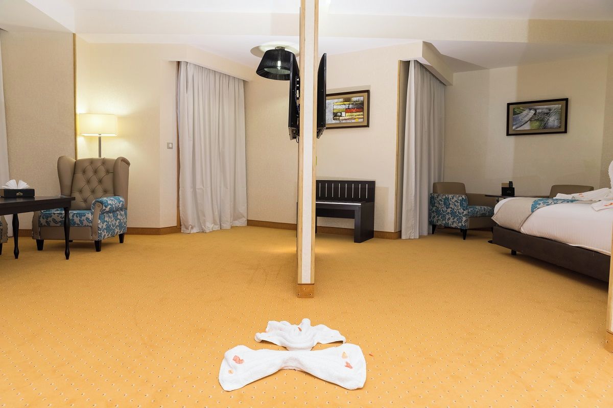 Una habitación de hotel con cama, escritorio, silla, lámpara de pie y lámpara de suelo.